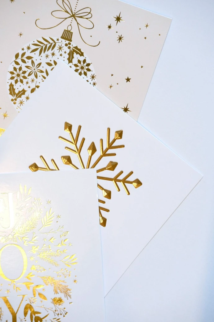 Golden christmas ornaments and snowflake designs on cards.